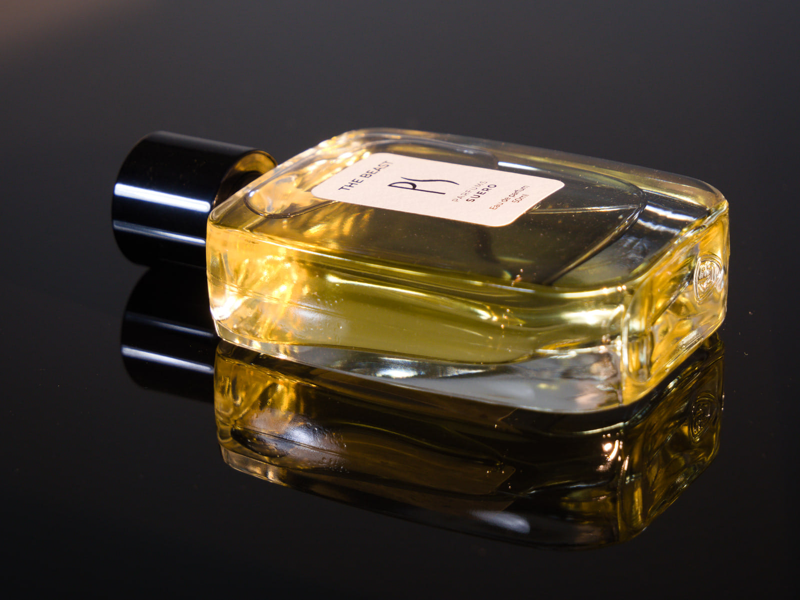 Flacon du parfum The Beast posé sur une surface réfléchissante