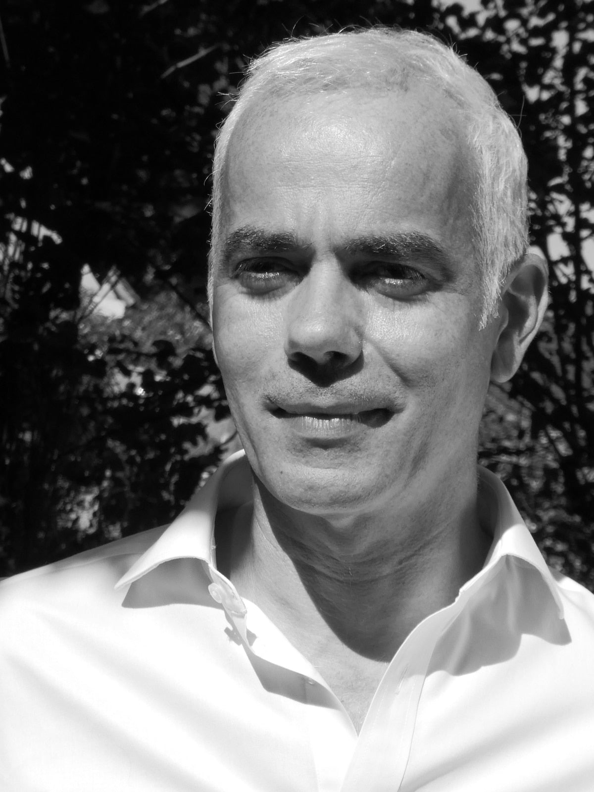 L'auteur parfumeur Fabrice SUERO pose en chemise blanche dans un jardin au soleil