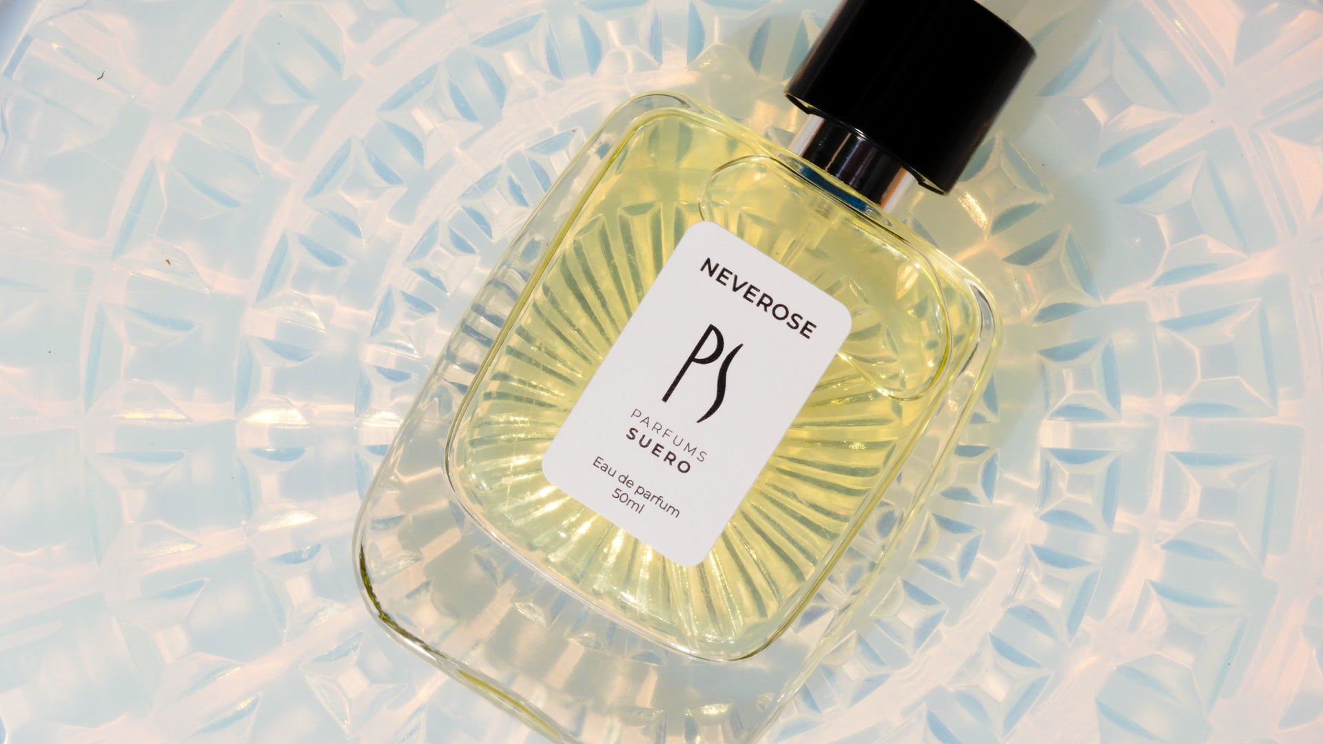Flacon de parfum Neverose posé au centre d'un élément en verre à motif