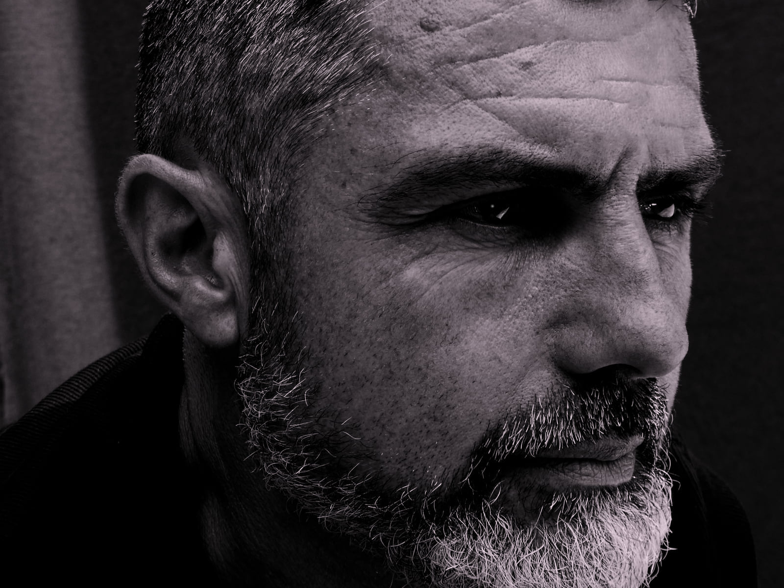 Zoom sur le visage d'un très bel homme mature pensif et concentré, ténébreux en noir et blanc