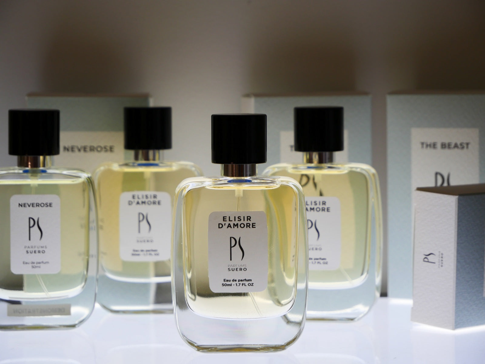 4flacons de parfum de la marque PARFUMS SUERO sur un socle lumineux avec leurs boites
